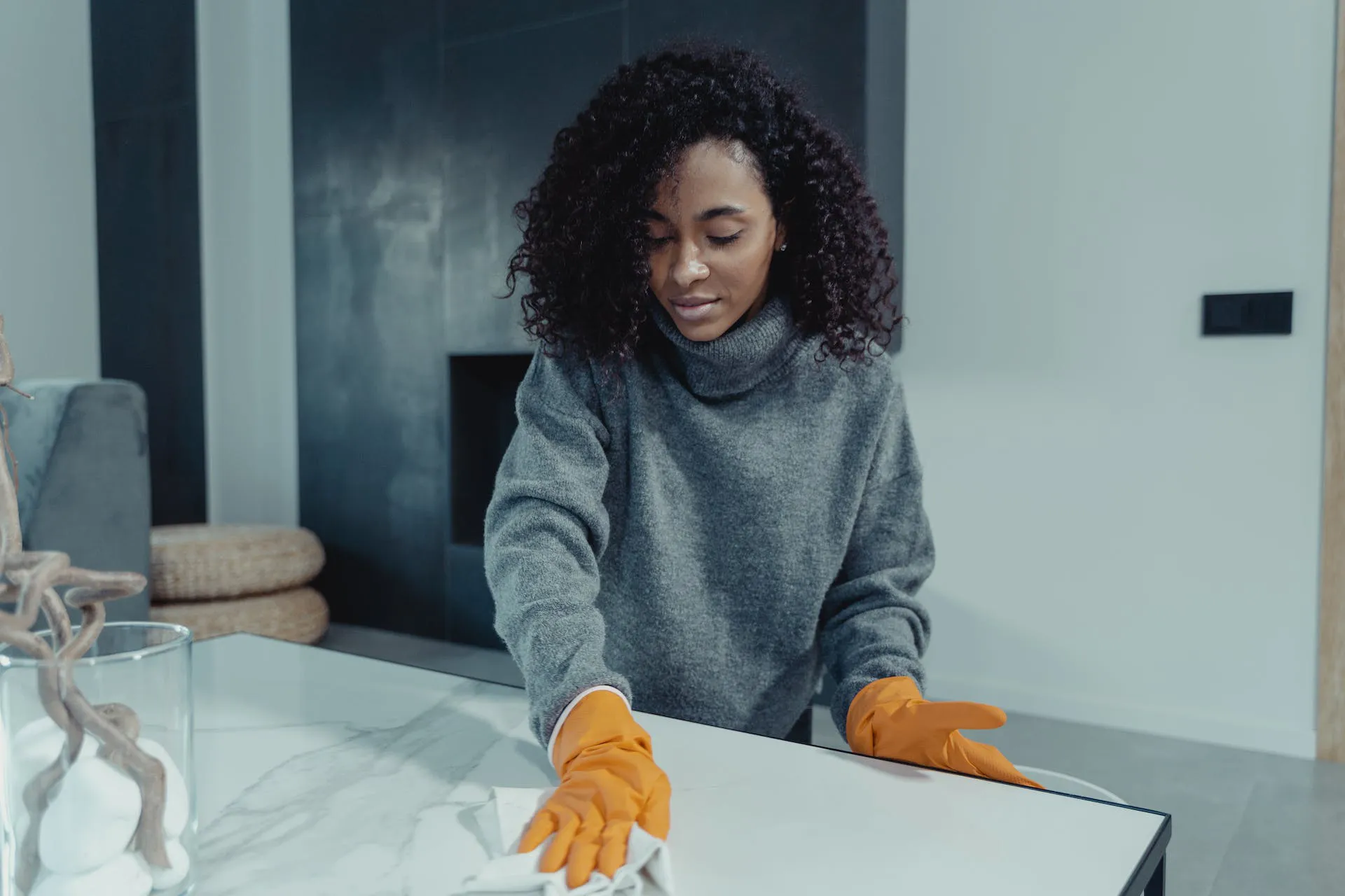 A woman who is a professional cleaner swipes a surface clean with a cleaning cloth